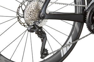 Close-up of an EVOLUZIONE 1s rear wheel showing gears, chain, and disc brake on its sleek, aerodynamic black frame.