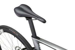 Close-up of a black bicycle saddle and seat post on the sleek EVOLUZIONE 1 Carbon, highlighting its aerodynamic design near the rear tire.