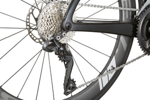 Close-up of the EVOLUZIONE 1 rear derailleur and gear cassette featuring an aerodynamic design with a black frame and gray wheel spokes.