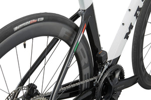 Close-up of the EVOLUZIONE 1 frame, showcasing its aerodynamic design with rear tire, chain, and Italian flag detail.