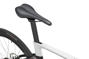 Close-up of EVOLUZIONE 1s sleek black saddle on a white frame, showcasing its aerodynamic design and high-performance rear disc brake.