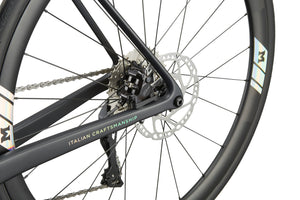 Close-up of the GRAN CORSA carbon road bike’s rear wheel, disc brake, chain, and Italian craftsmanship on the frame.