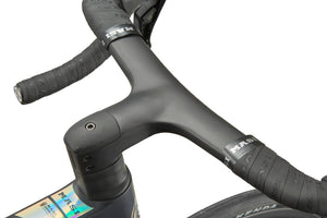 Close-up of GRAN CORSA’s integrated handlebar and stem, textured bar tape, and part of the carbon front wheel visible.