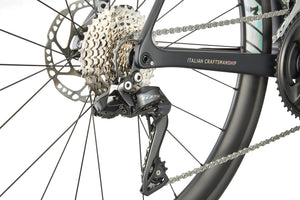 Close-up of the GRAN CORSA carbon road bikes rear derailleur, cassette, and chain with ITALIAN CRAFTSMANSHIP on the frame.
