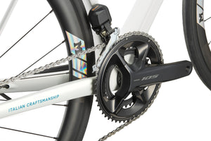 Close-up of a GRAN CORSA crankset and chain, with ITALIAN CRAFTSMANSHIP on the white carbon frame.