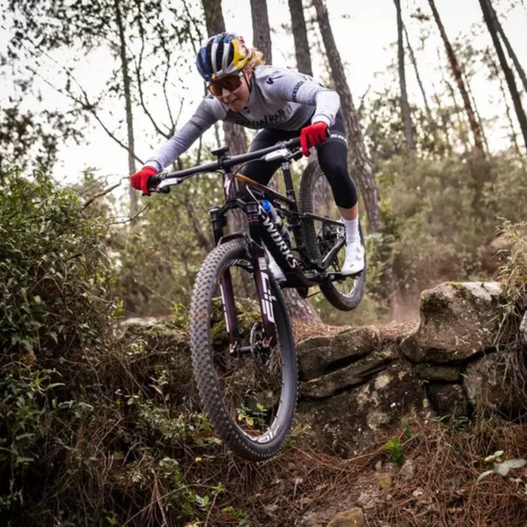 Person riding an S-works Specialized mountain bike on a rocky trail in a forest