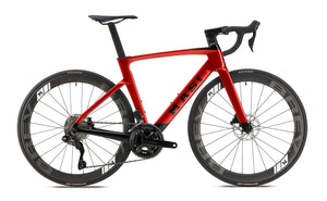 The Masi Bikes EVOLUZIONE 1 is a sleek, red road bike with an aerodynamic design, featuring black handlebars, high-performance gears, Kenda tires, and bold Masi lettering on the frame.