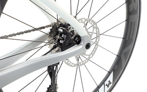 Close-up of the Masi Bikes EVOLUZIONE 1s rear wheel and gear system, showcasing an aerodynamic design with a disc brake and black spokes, highlighting the road bikes mechanical details and sporty features.